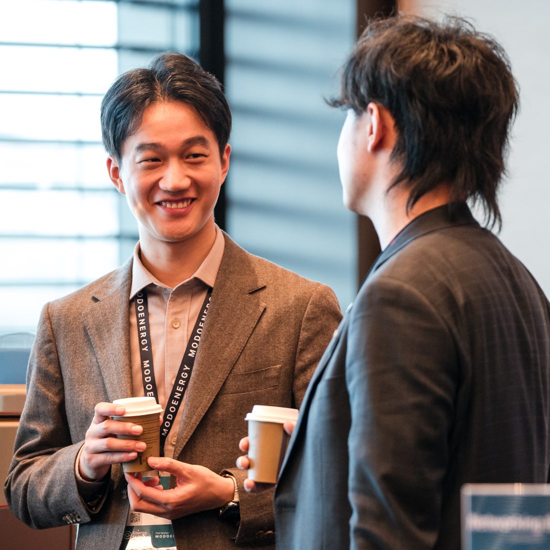 A real photograph from the client library, two colleagues talking over coffee at a conference
