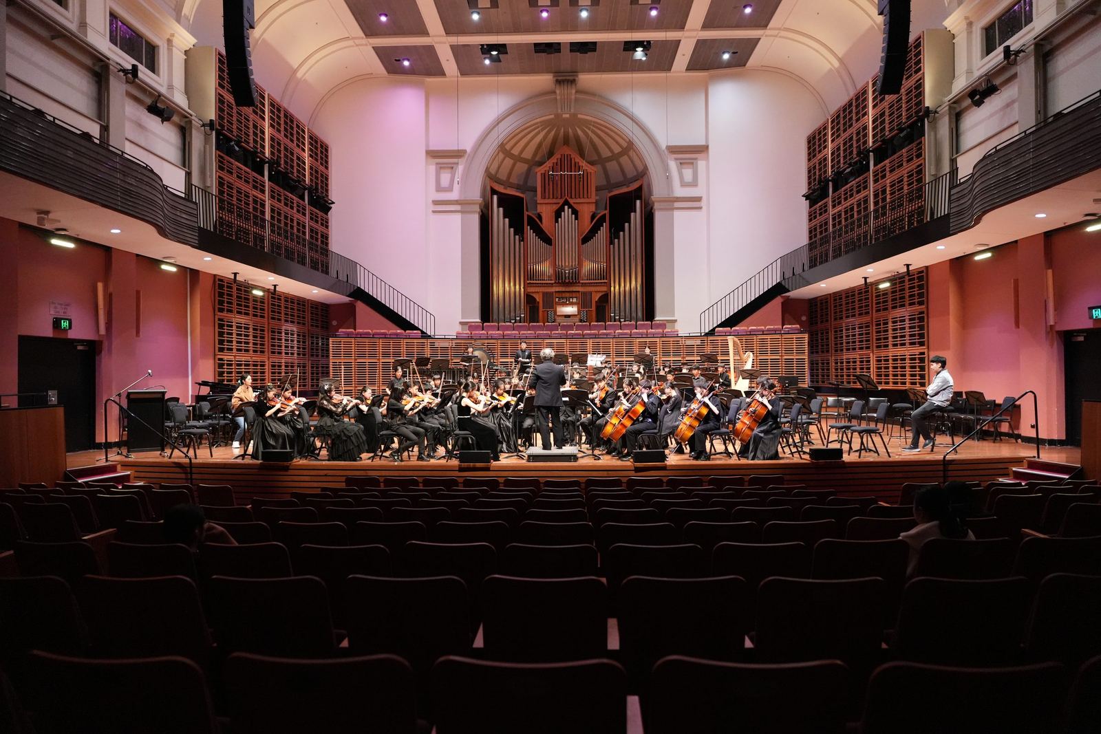 Orchestra on stage beneath the pipe organ, wide from the stalls