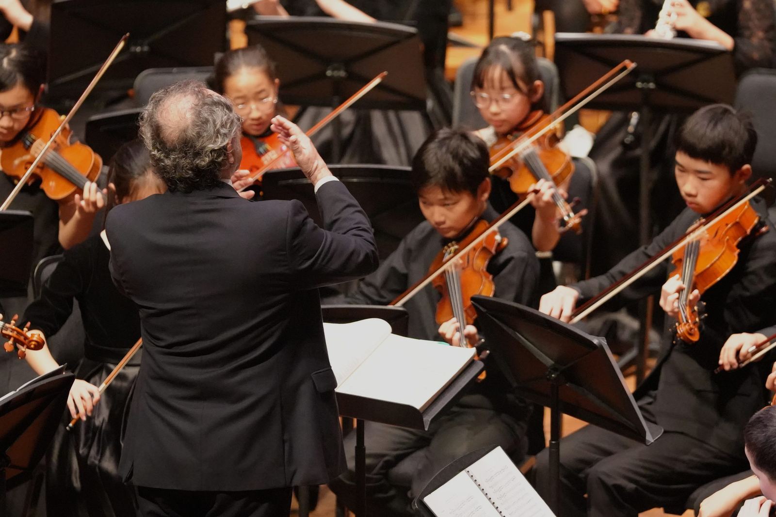 Conductor from behind, young violinists following the beat