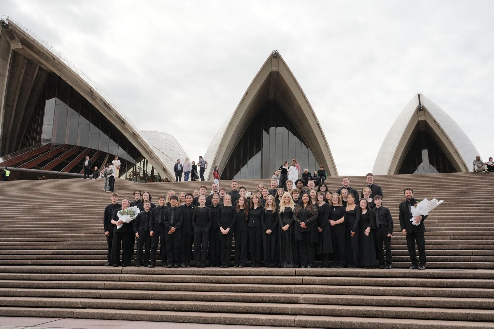 The ensemble on the Opera House steps holding flowers