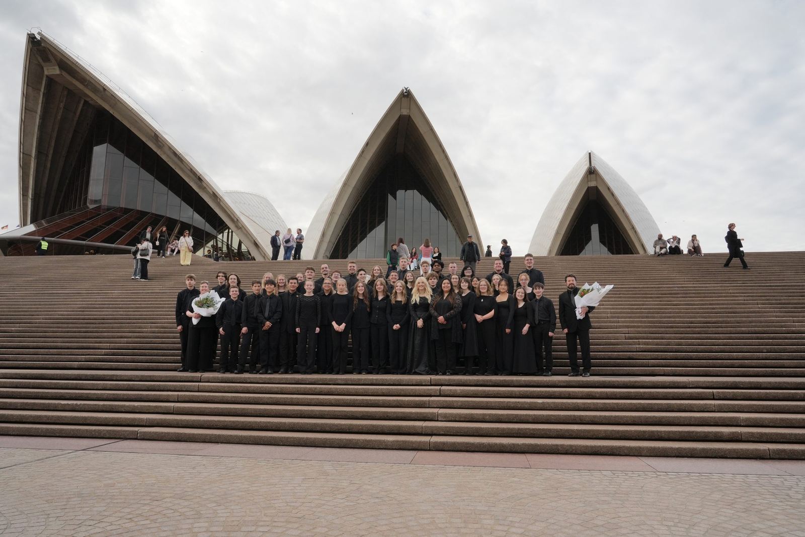 The ensemble on the steps with the sails behind